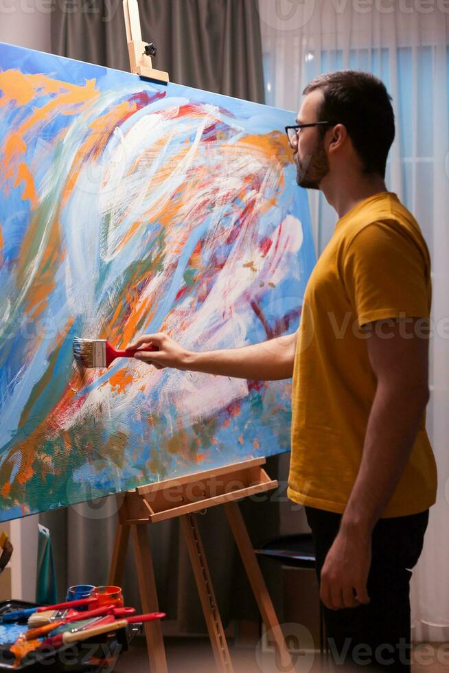 Artist with glasses painting a masterpiece in art workshop. Modern artwork paint on canvas, creative, contemporary and successful fine art artist drawing masterpiece photo