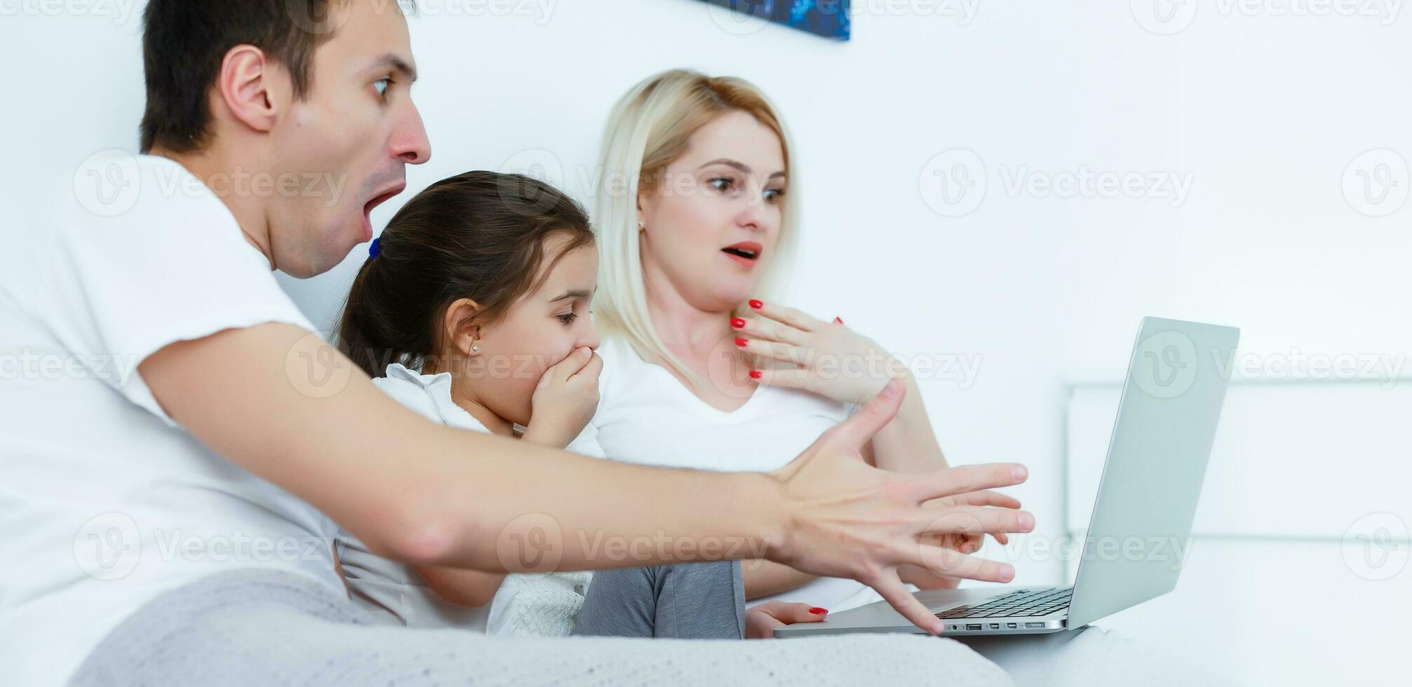 Happy family lies on bed and watching something on laptop. photo