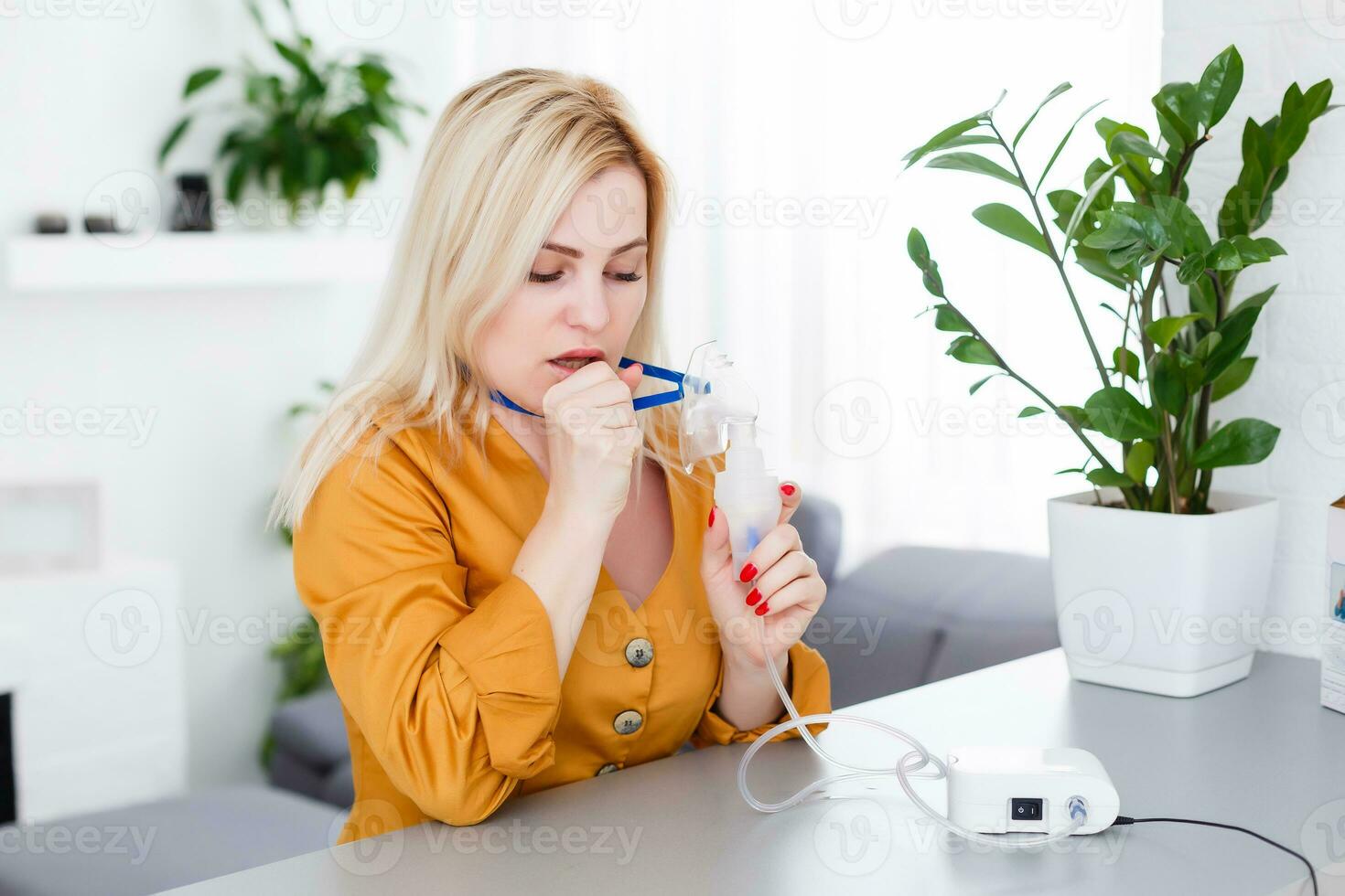 woman makes inhalation nebulizer at home. holding a mask nebulizer inhaling fumes spray the medication into your lungs sick patient. self-treatment of the respiratory tract using inhalation nebulizer photo