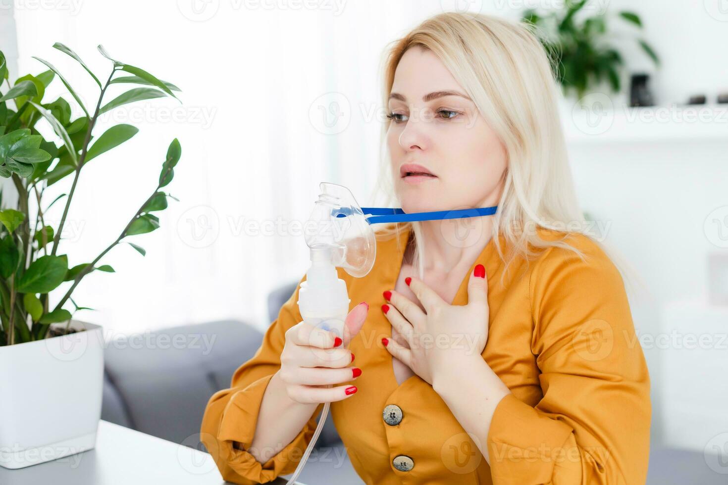 Sick beautiful female holds nasal mask with respiratory problem in hospital room. woman patient inhalation therapy by the mask of inhaler with soft stream smoke from bronchodilator. photo