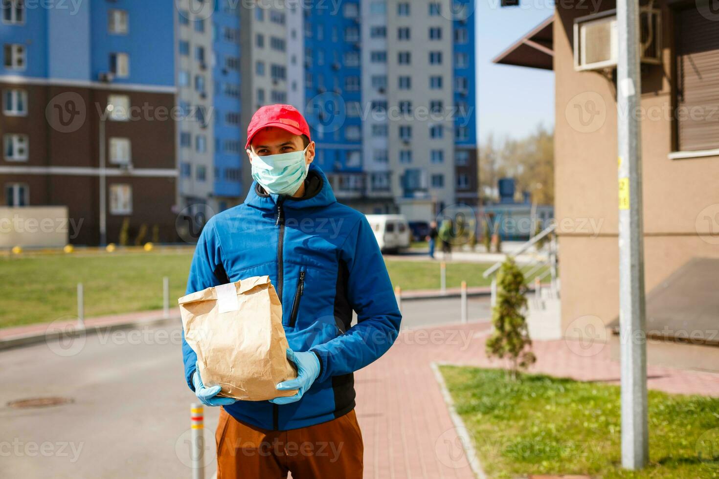Delivery man holding paper bag with food, food delivery man in protective mask photo