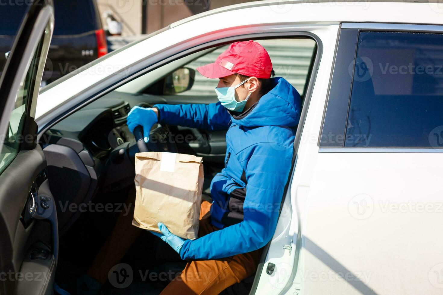 Courier in protective mask and medical gloves delivers takeaway food. Delivery service under quarantine, disease outbreak, coronavirus covid-19 pandemic conditions. photo