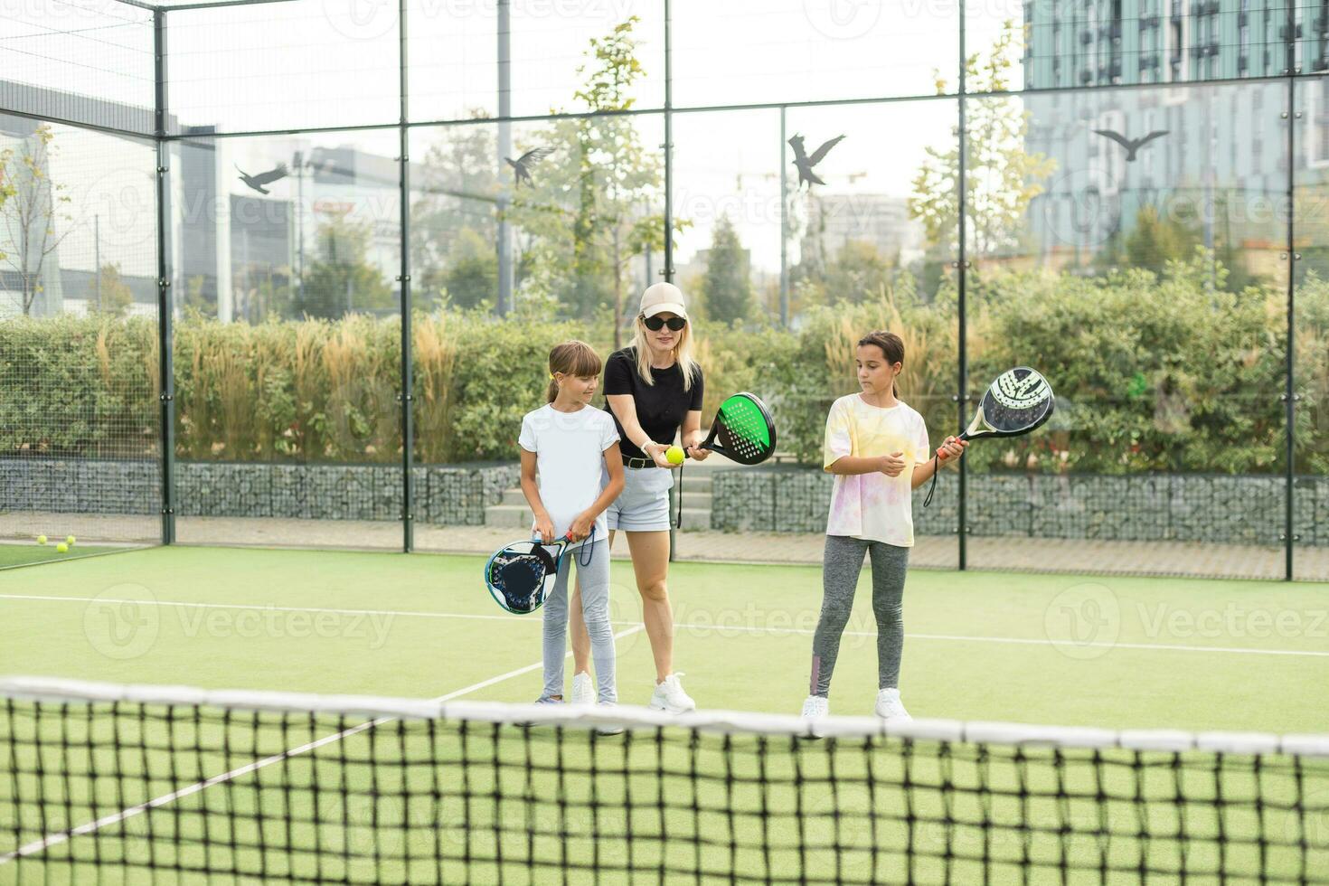 Active young woman practicing Padel Tennis with group of players in the tennis court outdoors photo