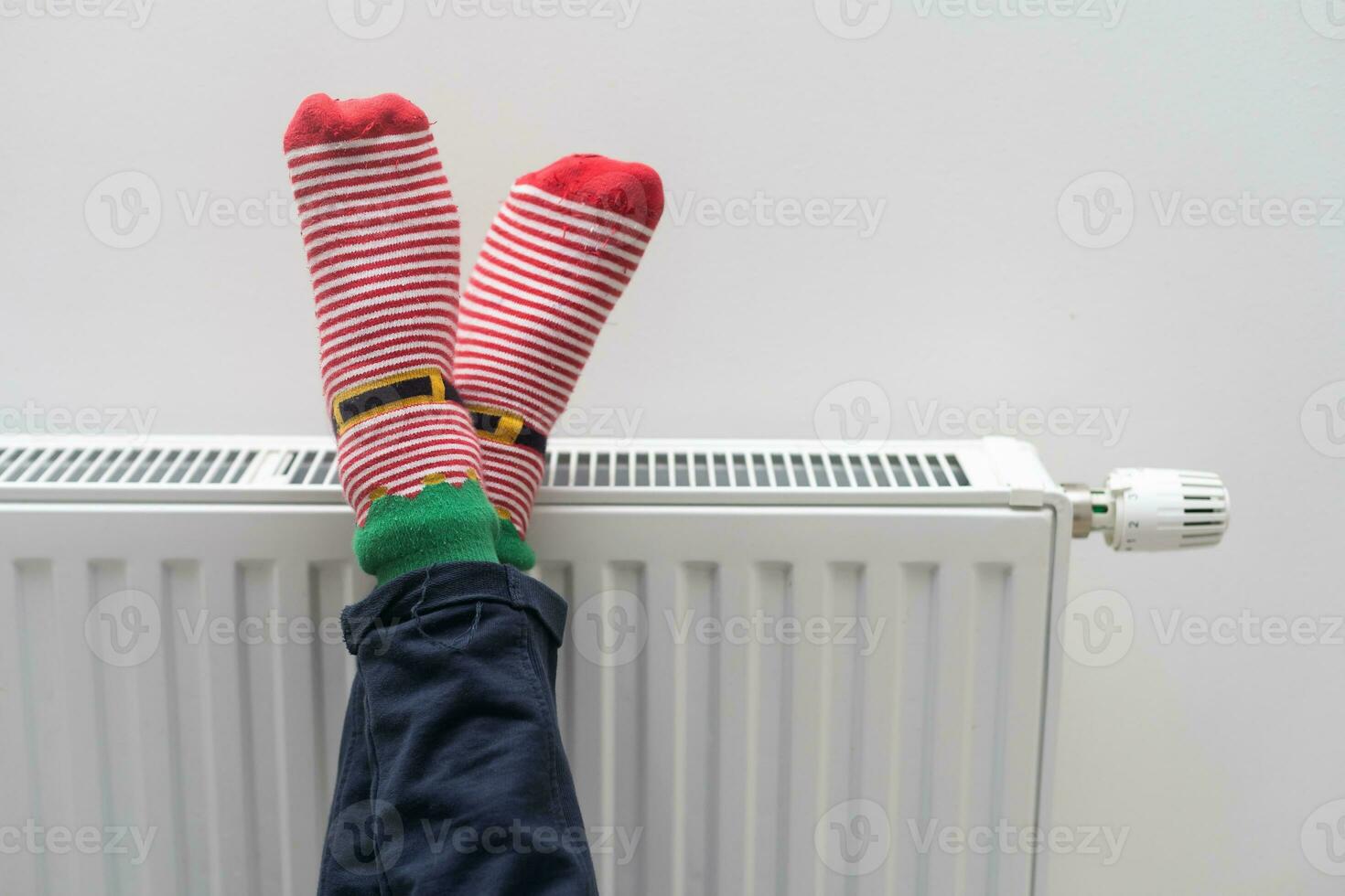 Children's feet in warm socks on a radiator. Girl warming up in a cold apartment photo