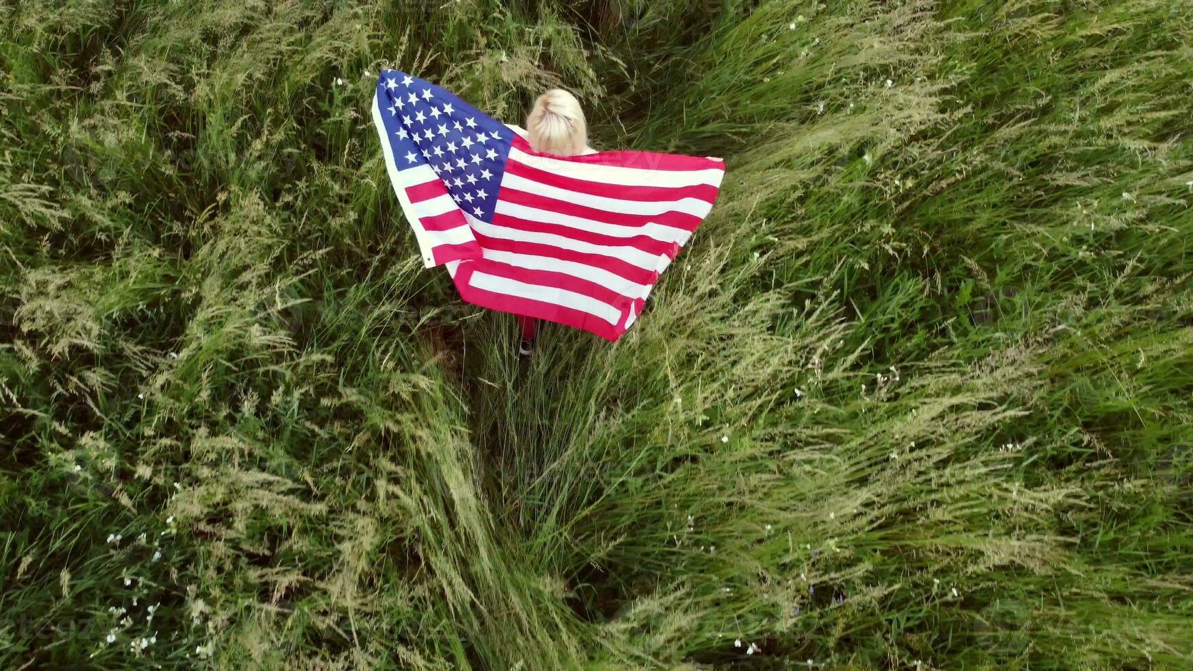 full length blond Woman holding American Flag in trees shadow of sunlight Back view cute blondy girl run on fresh green grass texture photo