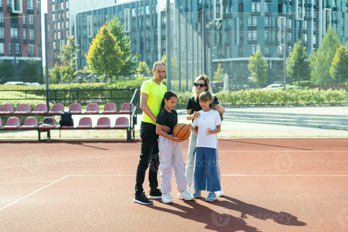 verano vacaciones, deporte y personas concepto contento familia con pelota jugando en baloncesto patio de recreo foto