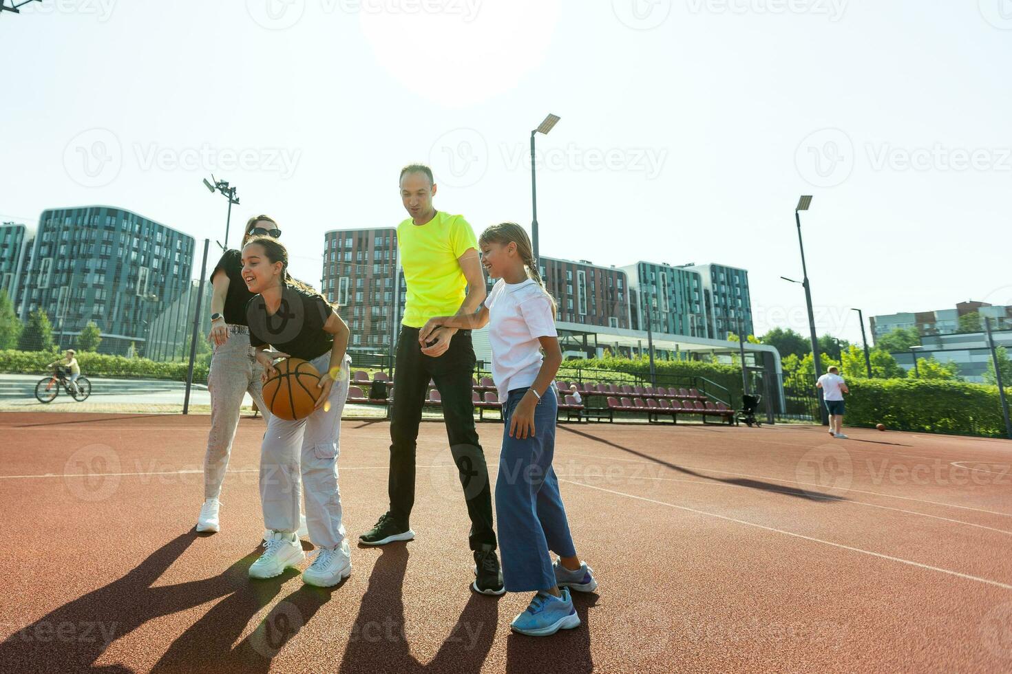 verano vacaciones, deporte y personas concepto contento familia con pelota jugando en baloncesto patio de recreo foto