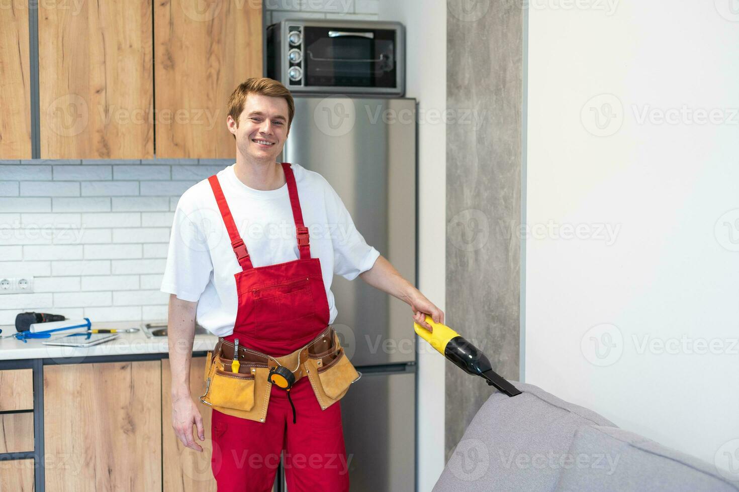 Handsome young man cleaning furniture. Process of deep furniture cleaning, removing dirt from sofa. Washing concept photo