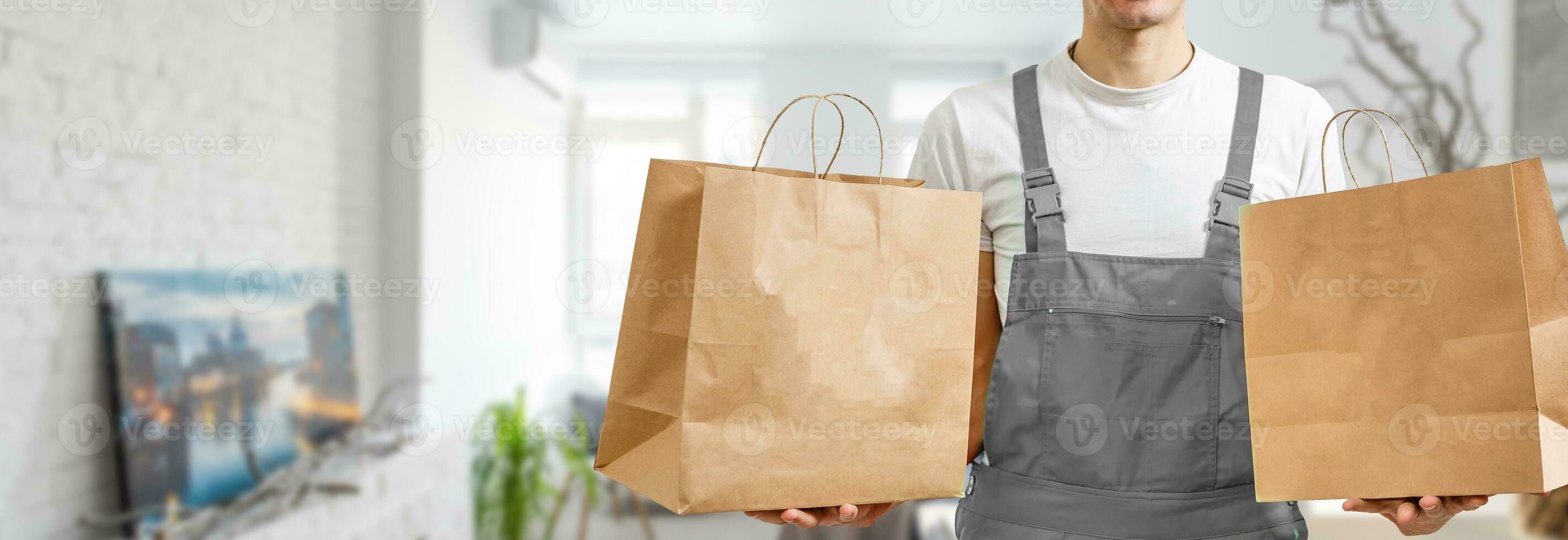 Paper pocket and food containers in hands of a smiling deliveryman. Quality service of a restaurant. photo