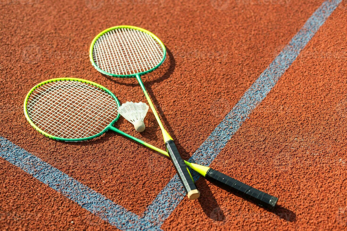 Badminton shuttlecocks and racket, placed in the corner of a synthetic field. photo
