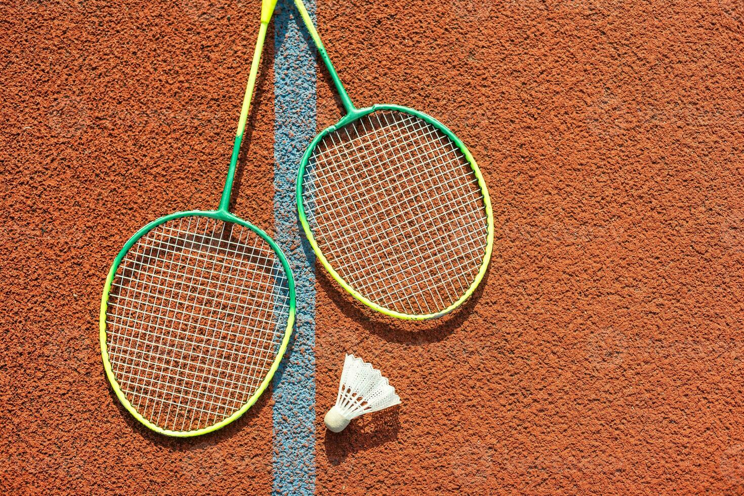Badminton rackets and feather shuttlecock on the court photo