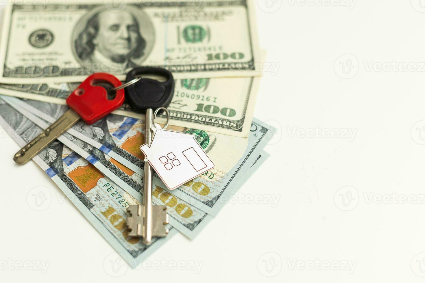 Two keys lie on scattered US dollar bills. The concept of buying real estate, mortgage, home acquisition. photo