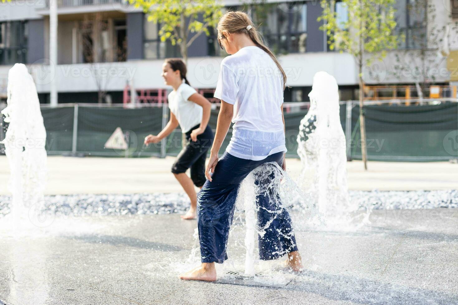 Happy kid playing in a fountain with water photo