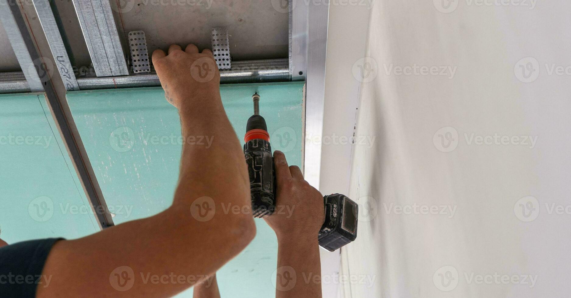 Workers fitting panel into frame of ceiling. photo