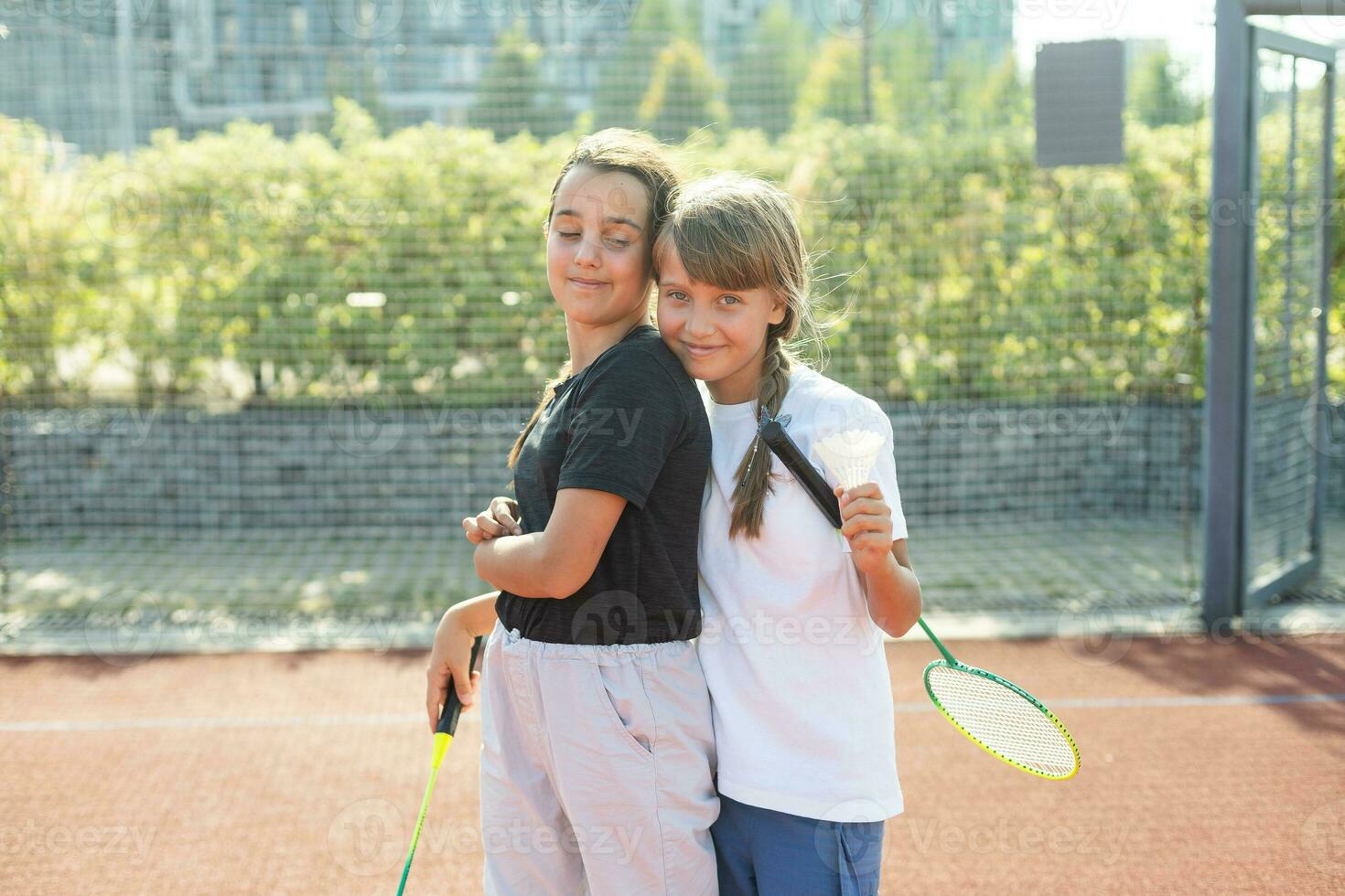 Two girls with badminton rackets on the football field. photo