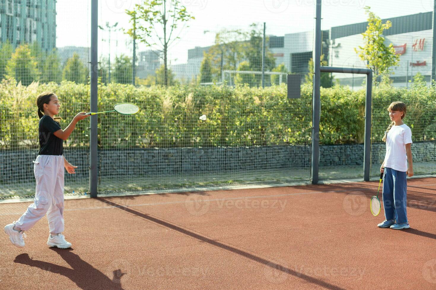 Two girls with badminton rackets on the football field. photo