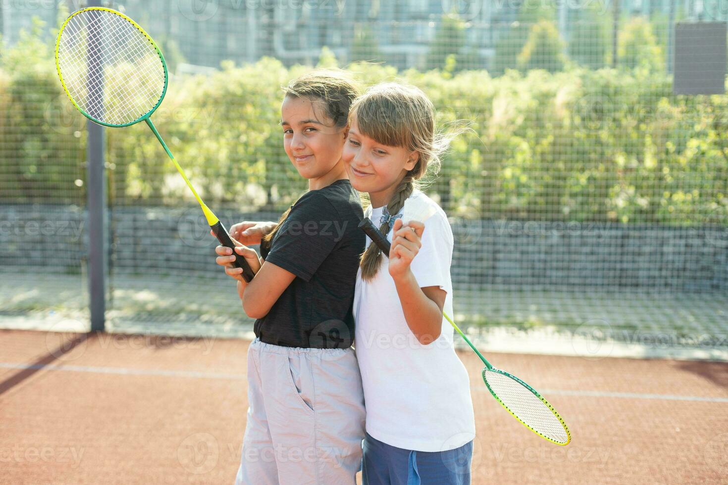 Two girls with badminton rackets on the football field. photo