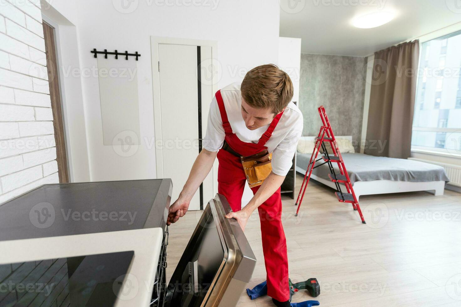 the master installs the washing machine, connects it to the water supply and drainage systems photo