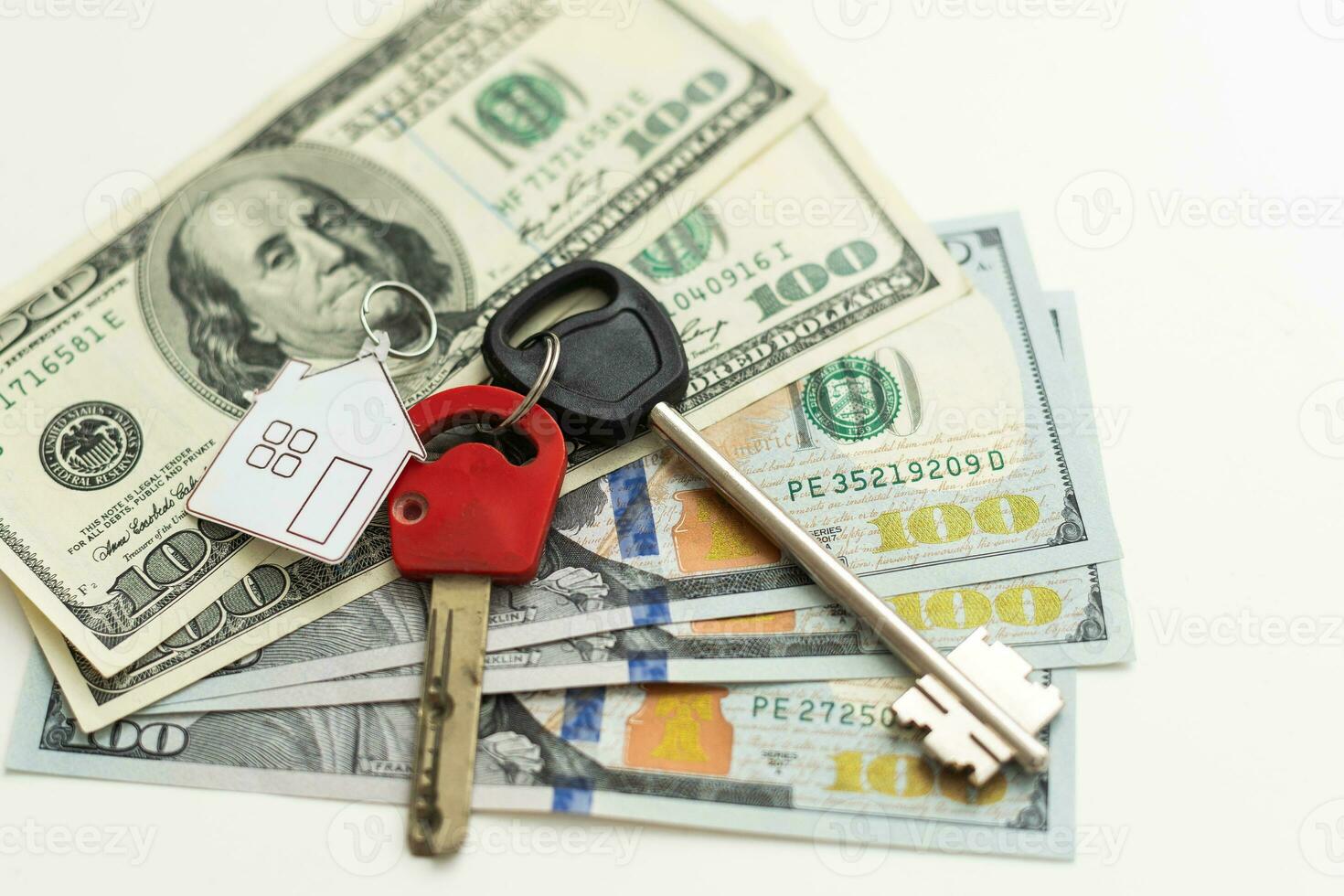 Two keys lie on scattered US dollar bills. The concept of buying real estate, mortgage, home acquisition. photo