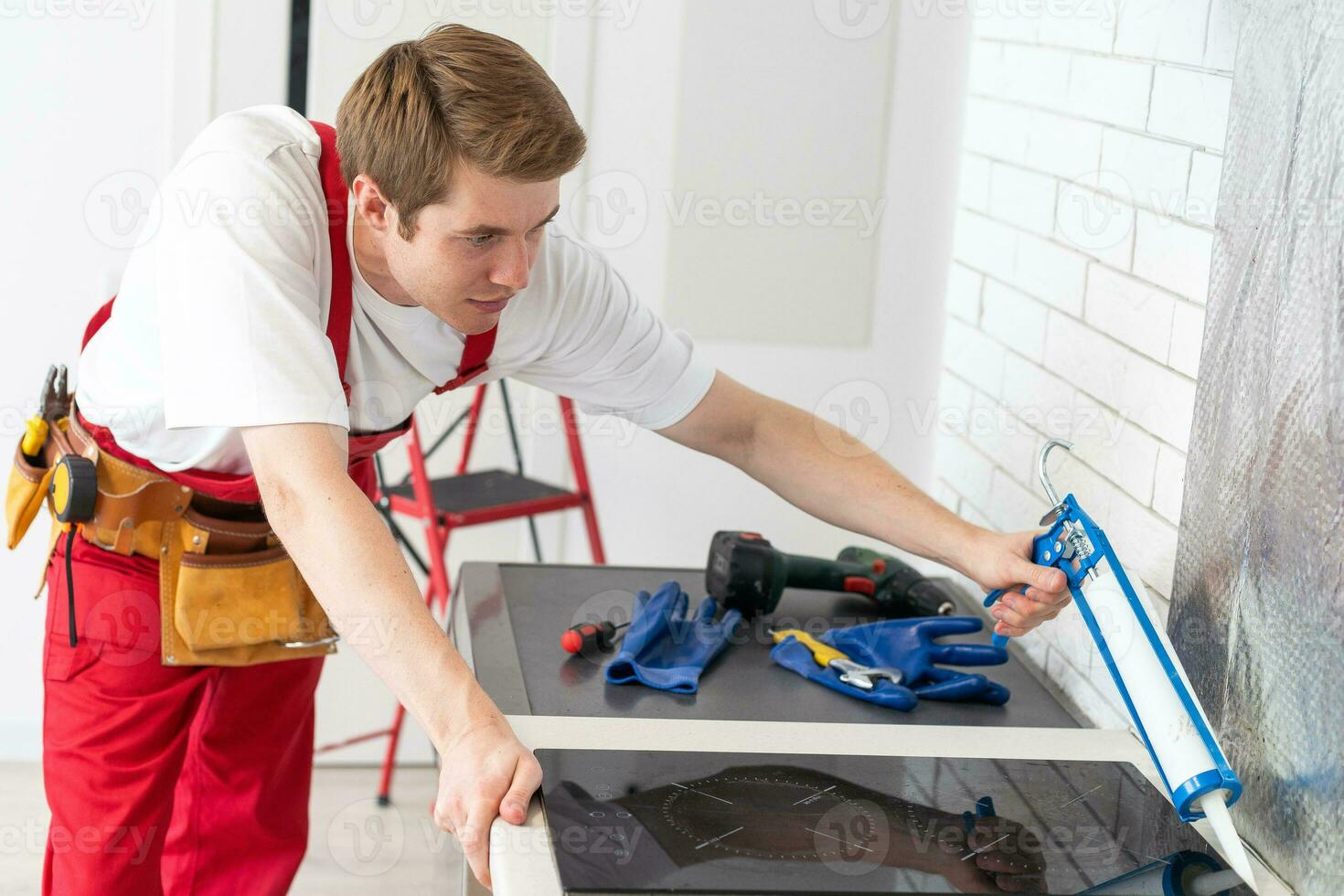 Young Repairman Installing Induction Cooker In Kitchen. photo