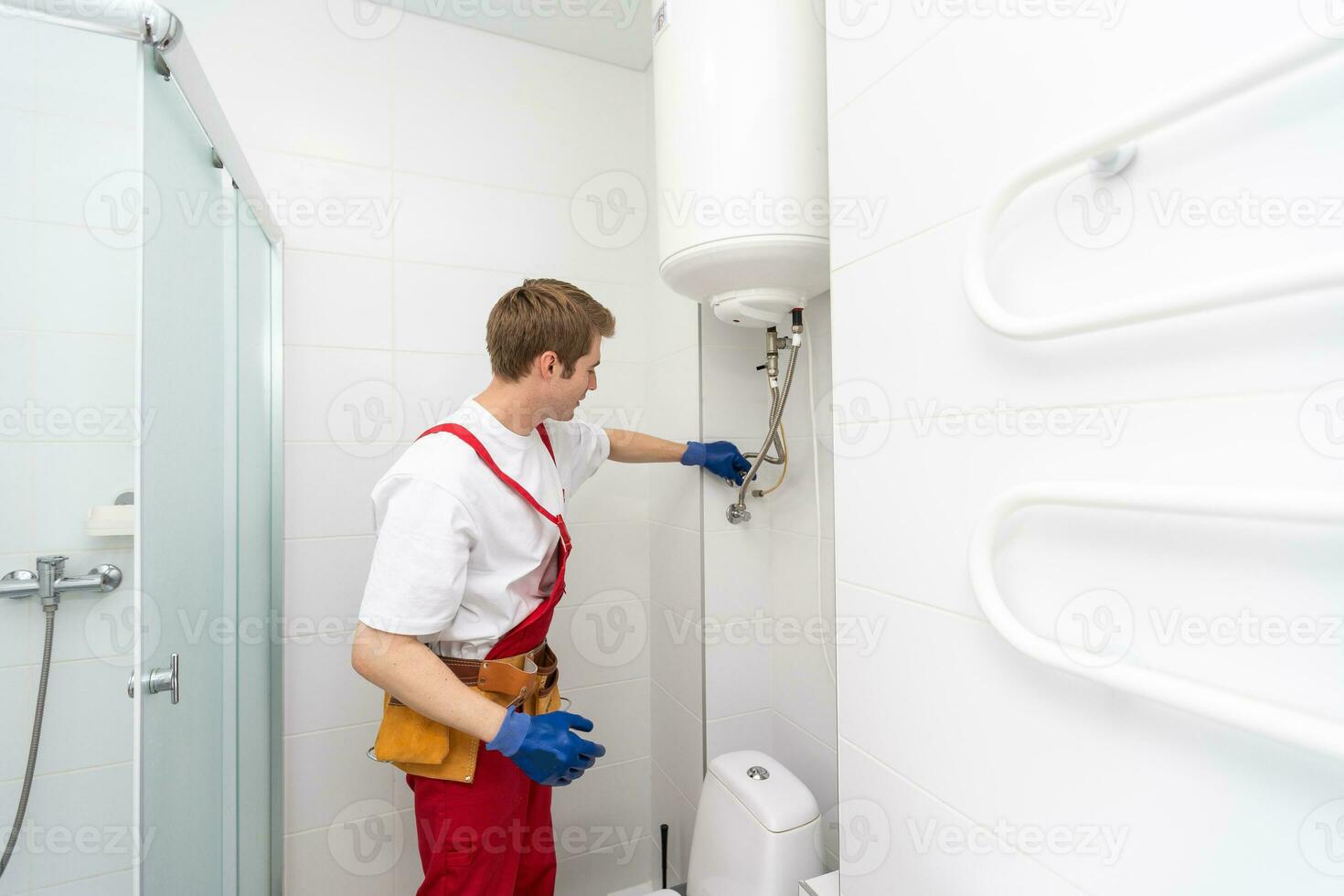 Closeup of plumber using screwdriver while fixing boiler or water heater, working on heating system in apartment photo