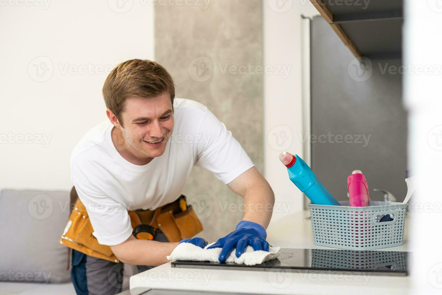 young cheerful man cleaning kitchen dirty household duty spray bottle dust indoors photo