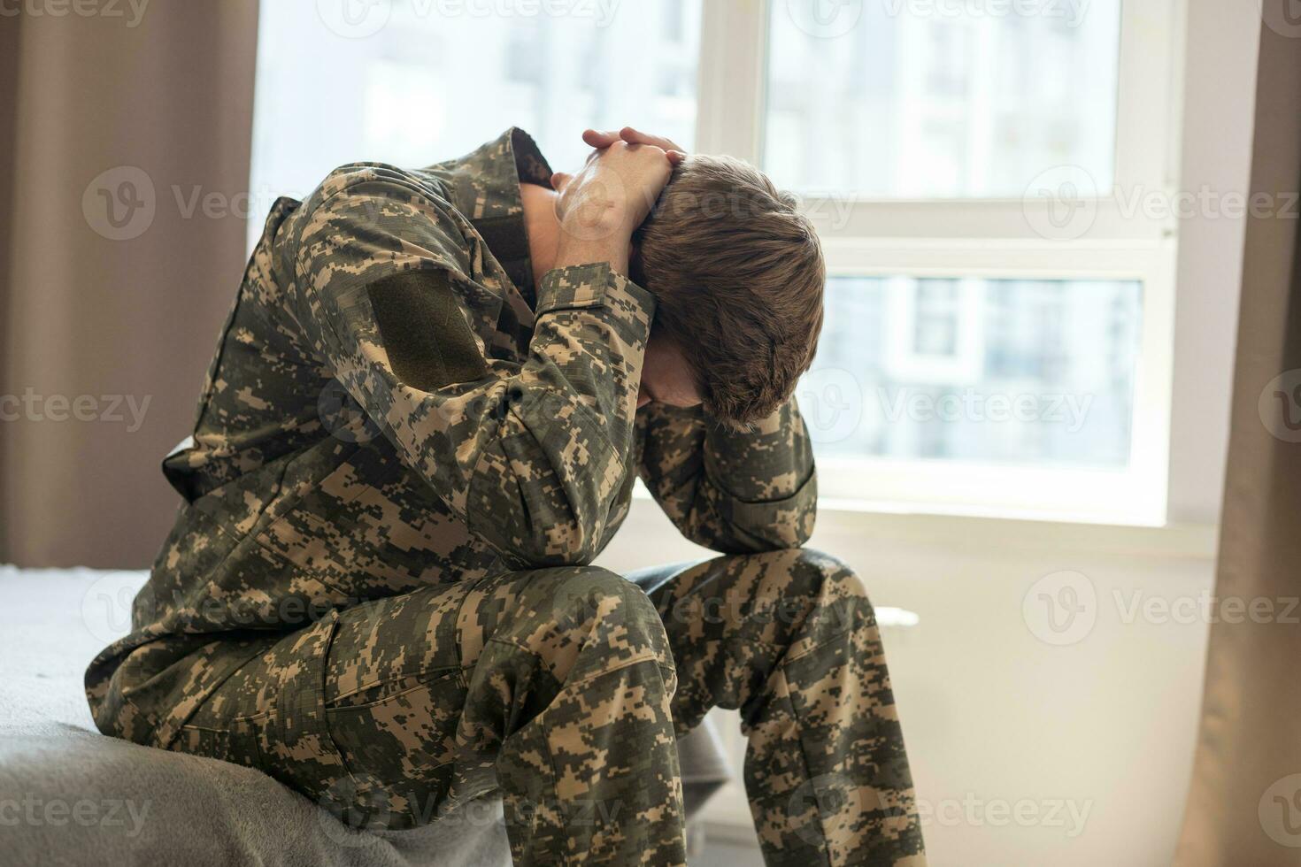 Nervous male military suffering depression, sitting alone at home, PTSD concept. photo