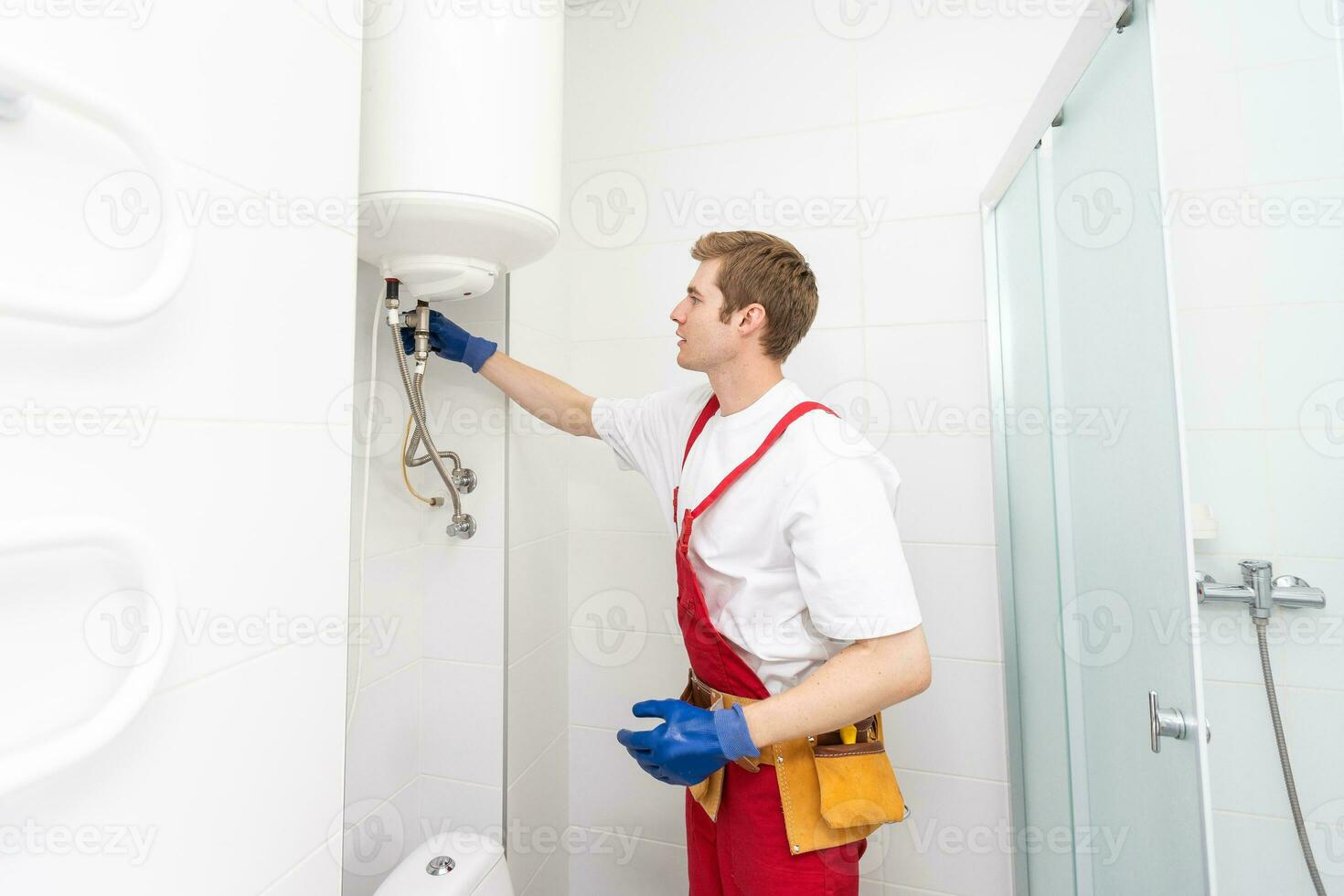 Closeup of plumber using screwdriver while fixing boiler or water heater, working on heating system in apartment photo