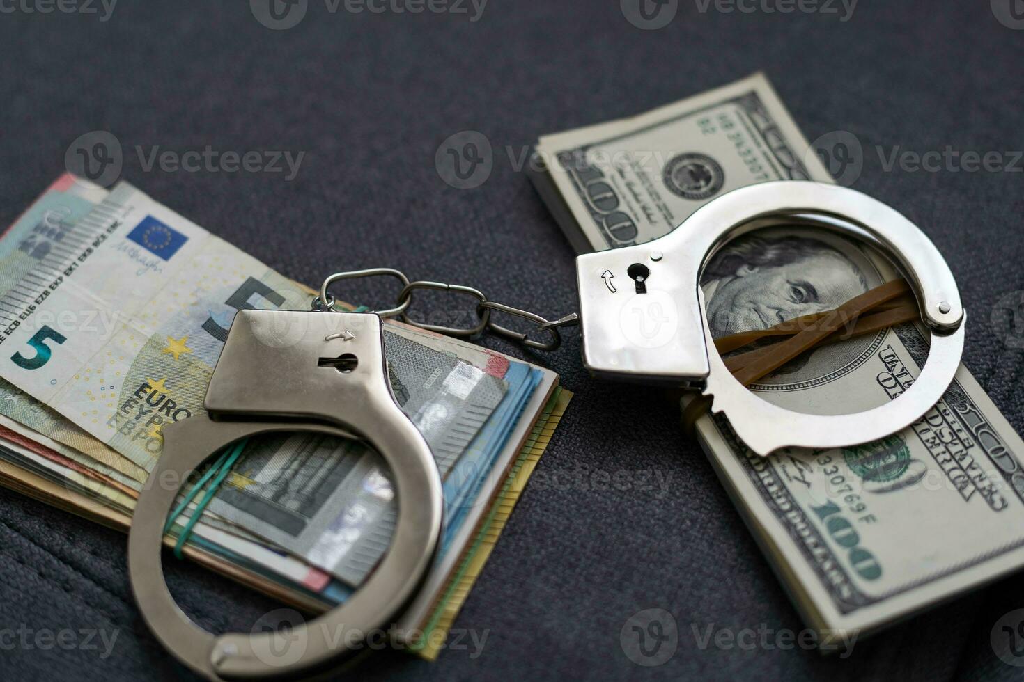 Police handcuffs lie on many dollar bills isolated on black background. Crime. justice and money. Concept of crime and corruption with handcuffs. photo