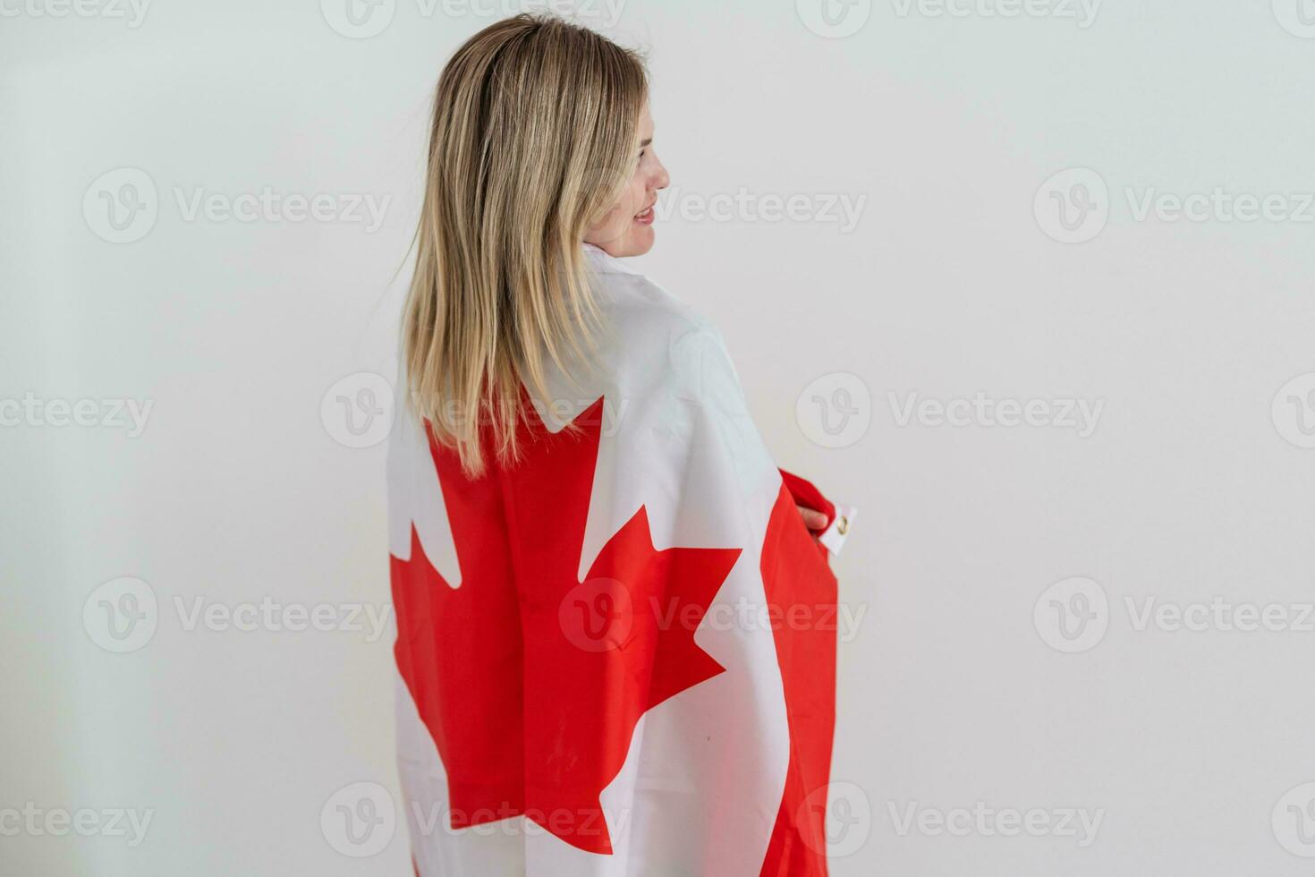 beautiful smiling woman covered in canadian flag looking at camera isolated on white photo