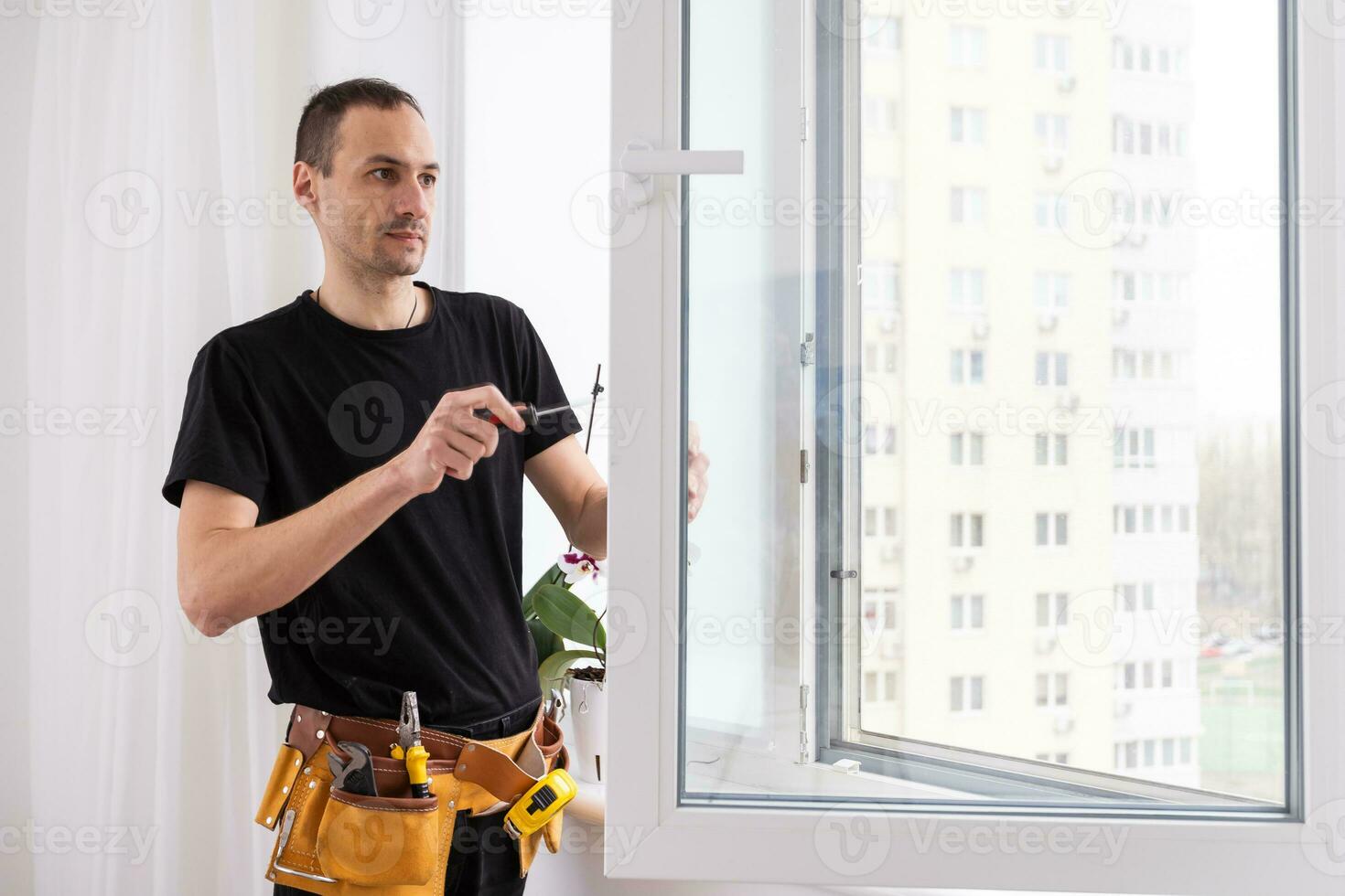 Master in gloves adjusting pvc windows with screwdriver closeup. Installation of plastic windows repair and maintenance concept photo
