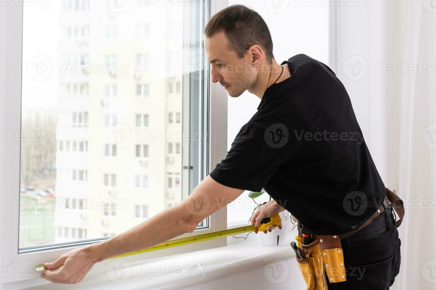 Master in gloves adjusting pvc windows with screwdriver closeup. Installation of plastic windows repair and maintenance concept photo