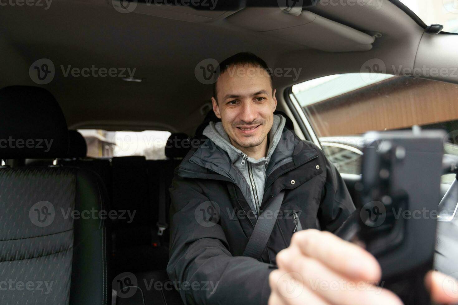 contento dueño. hermoso barbado maduro hombre sentado relajado en su recién compró coche mirando fuera el ventana sonriente alegremente foto