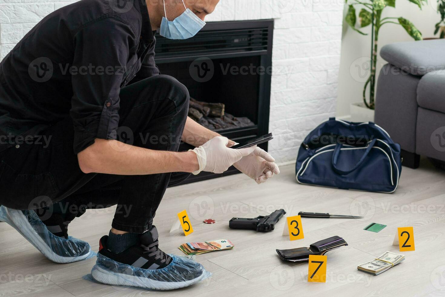 Young policeman collecting evidence standing behhind yellow crime scene tape photo