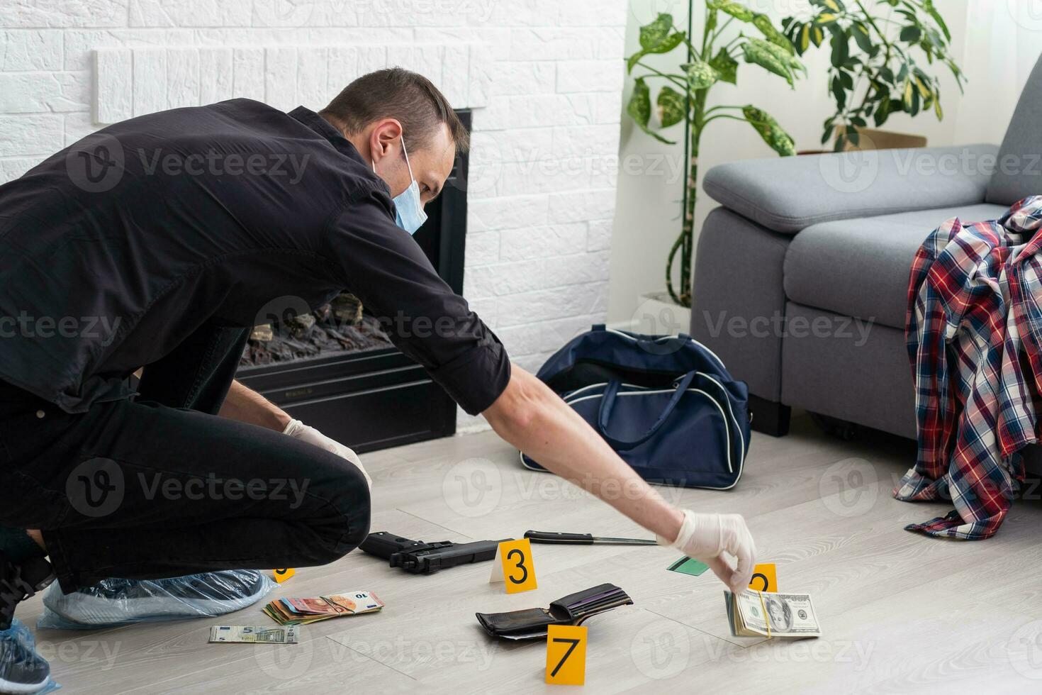 Young policeman collecting evidence standing behhind yellow crime scene tape photo