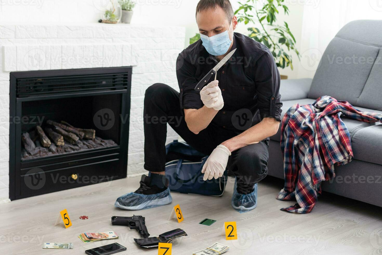 Young policeman collecting evidence standing behhind yellow crime scene tape photo