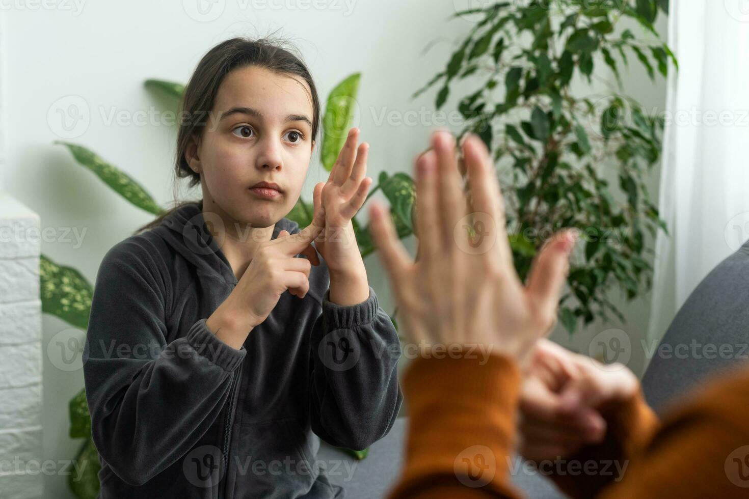 linda pequeño niña hacer mano gesto aprendizaje firmar idioma con mamá o hembra niñera, sonriente pequeño niño práctica no verbal hablar con profesor a hogar, preescolar discapacitado niño tener lección con tutor foto