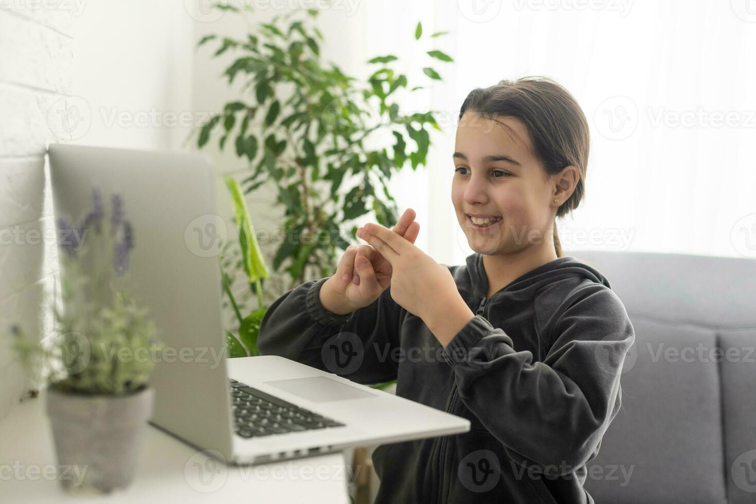 sonriente Adolescente niña sordo discapacitado niño colegio niña aprendizaje en línea clase en ordenador portátil comunicado con profesor por vídeo conferencia llamada utilizando firmar idioma demostración mano gesto durante virtual lección. foto