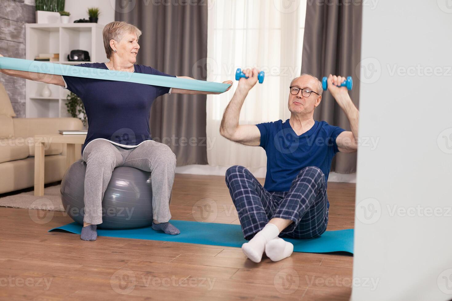 Elderly couple workout at home with elastic band and dumbbells. Old person healthy lifestyle exercise at home, workout and training, sport activity at home on yoga mat. photo