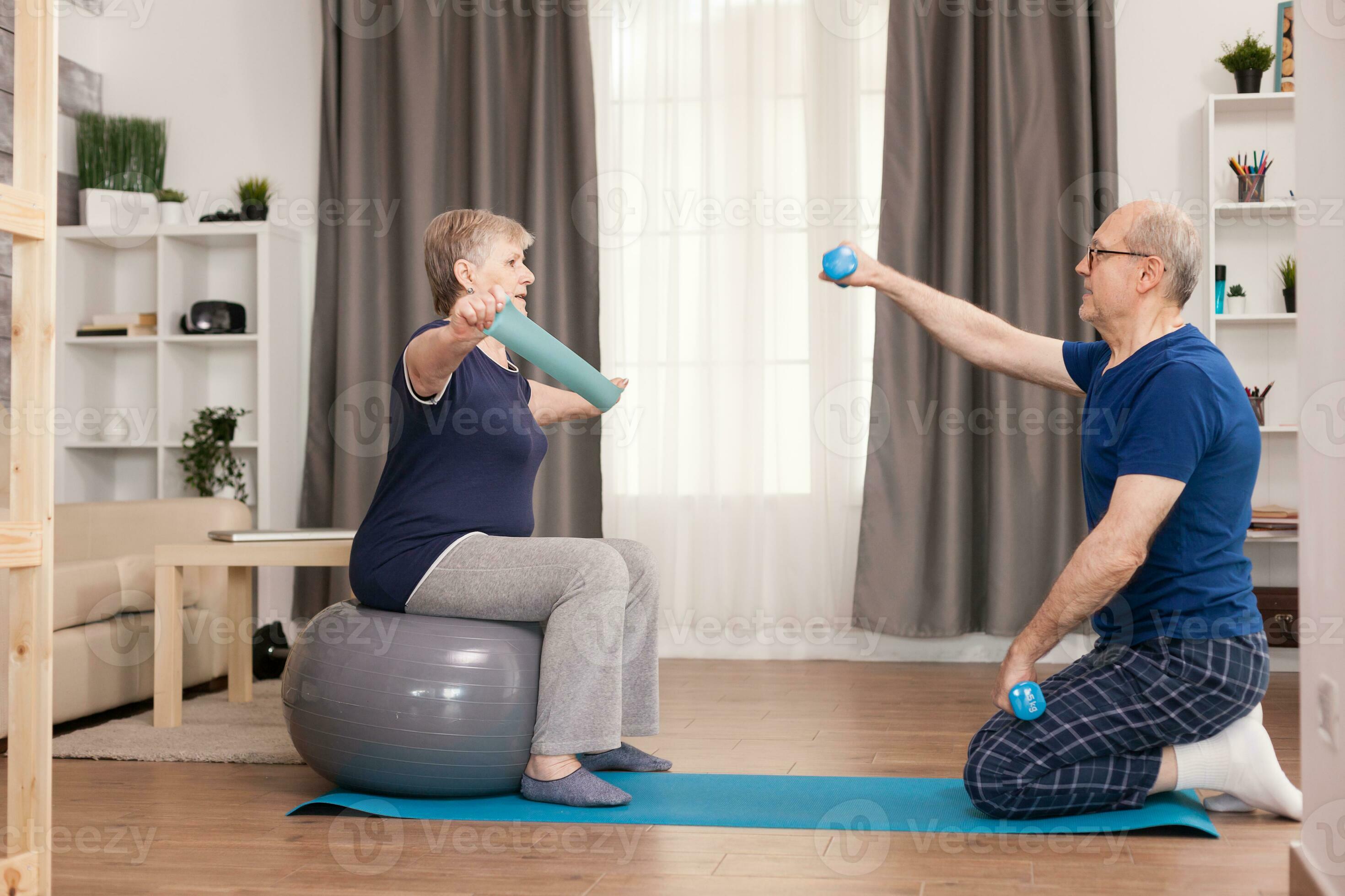 Energetic senior couple training in home using dumbbells and stability  ball. Old person healthy lifestyle exercise at home, workout and training,  sport activity at home on yoga mat. 35205305 Stock Photo at