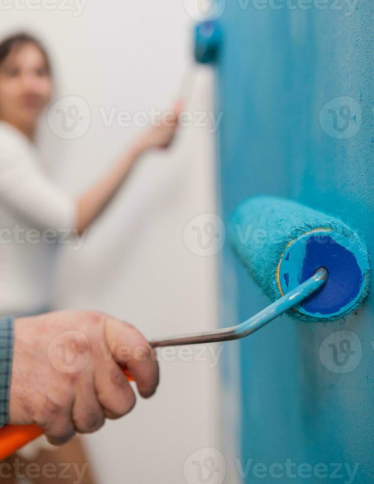 Close up of roller brush on the wall during renovation. Flat decoration and painting. Interior apartment improvement maintenance. Roller, ladder for house repair photo