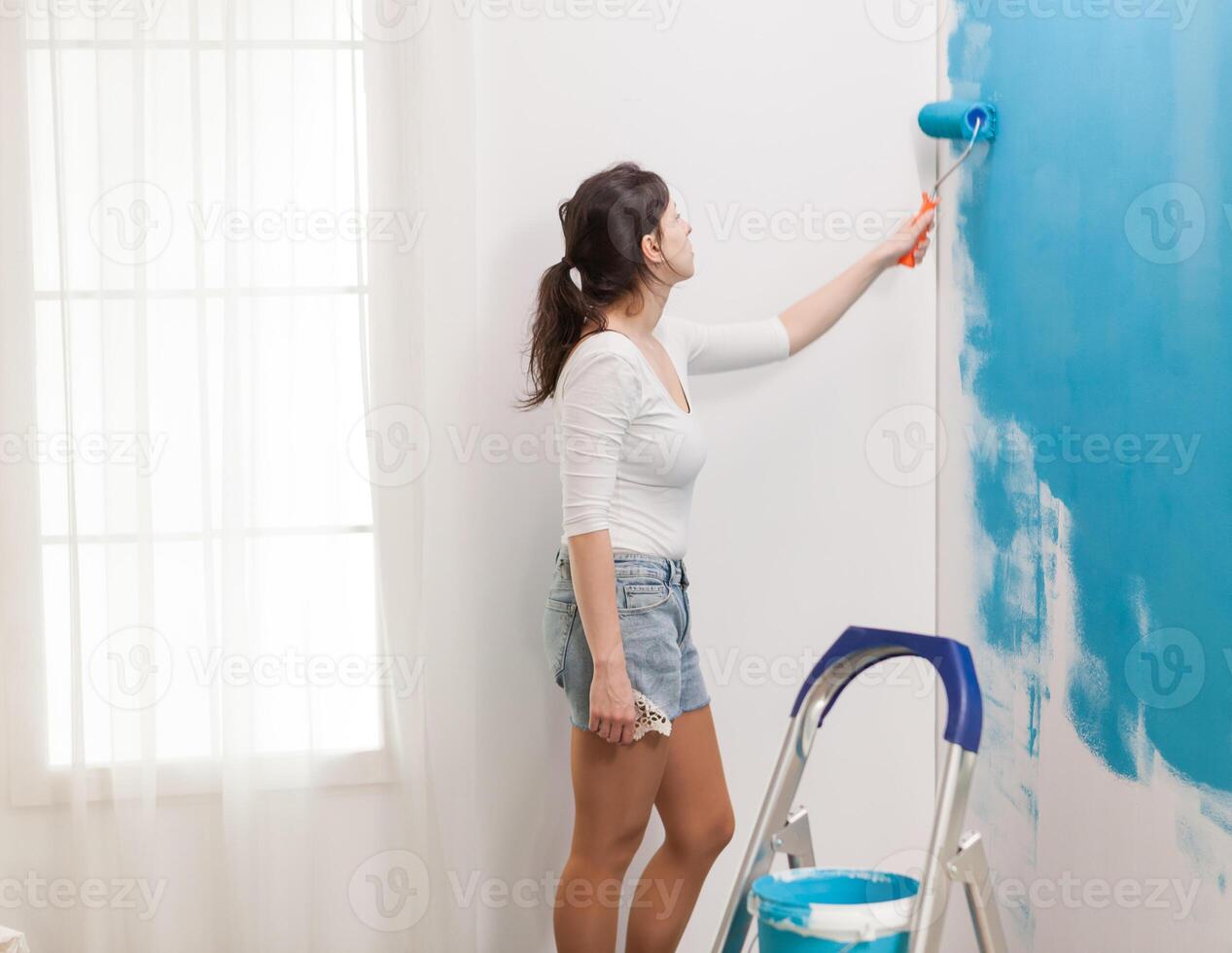 caucásico mujer redecorando Departamento y pintura paredes con rodillo cepillar. Departamento cambio de imagen redecoración y hogar construcción mientras renovando y mejorando. reparar y decorando foto