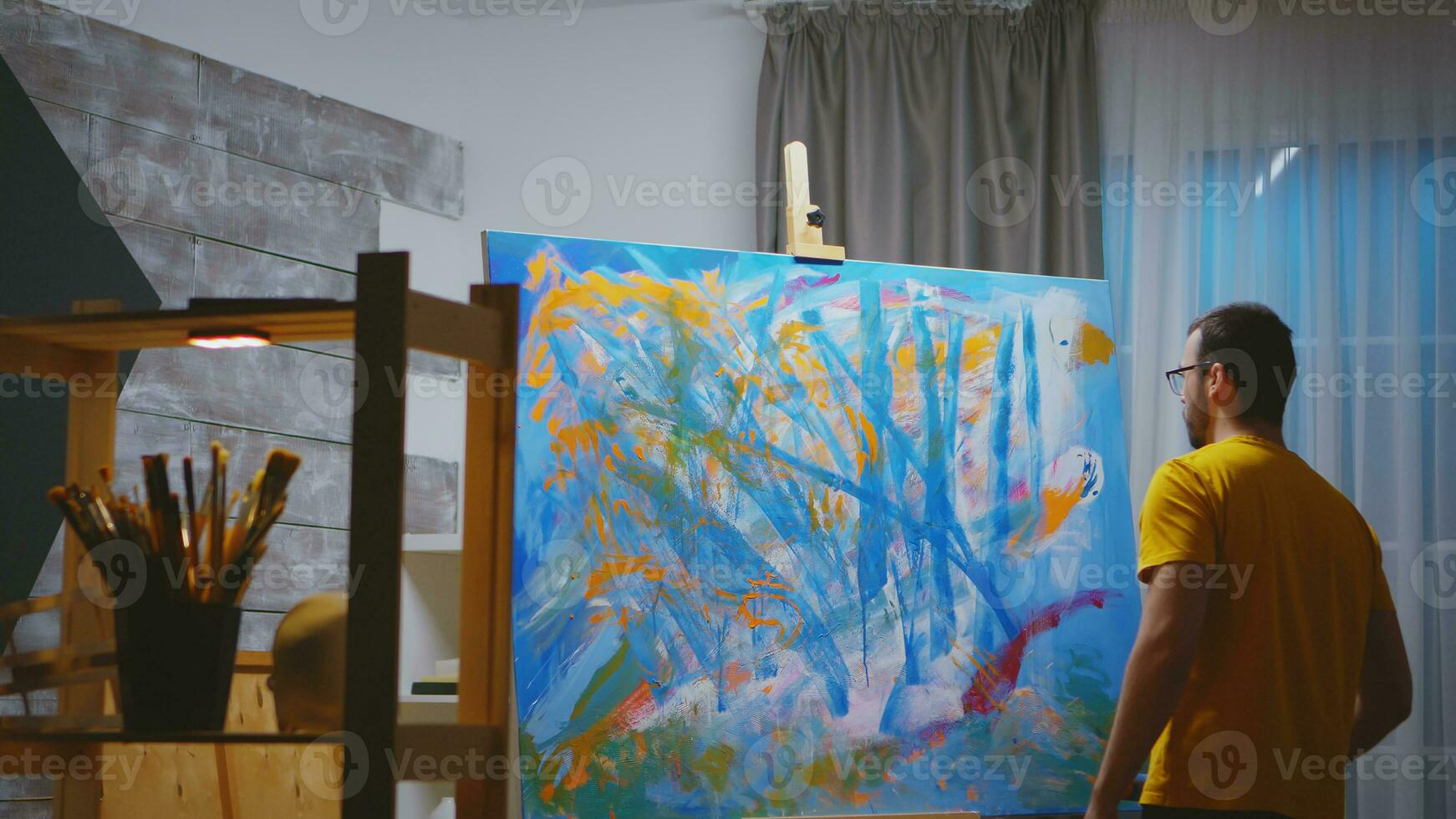 artista pintura con rodillo en grande lona en Arte taller. foto