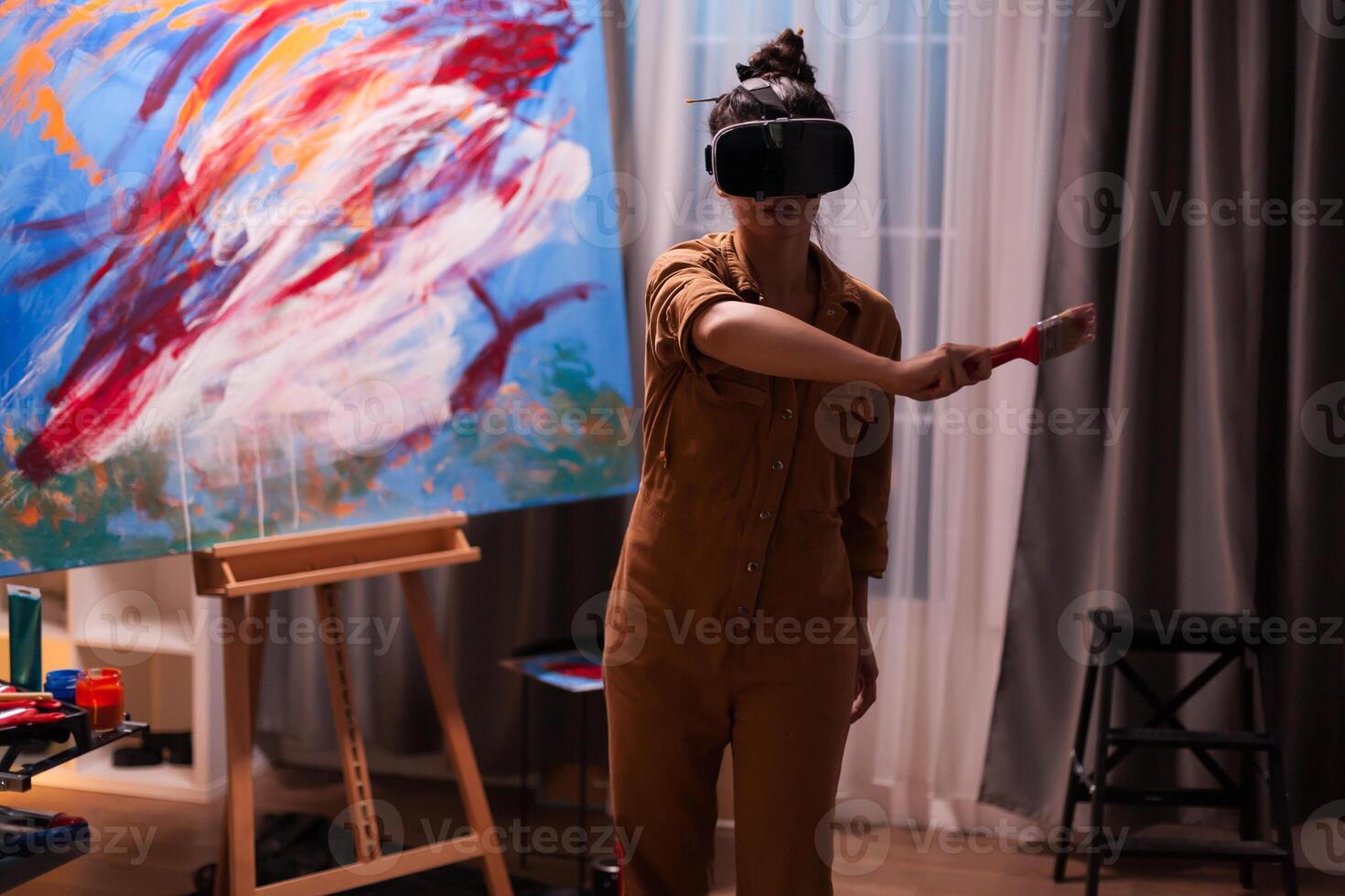 Painter using virtual reality headset in art studio creating a masterpiece. Modern artwork paint on canvas, creative, contemporary and successful fine art artist drawing masterpiece photo