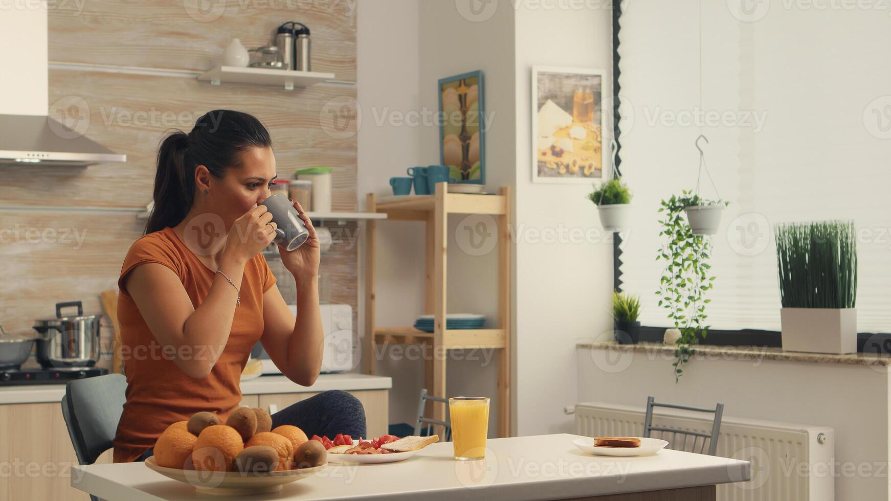 Taking a sip of coffee in the morning while enjoying delicious breakfast. Lady ejoying a cup of coffee in the morning. Happy housewife relaxing and spoiling herself with a healthy meal alone photo