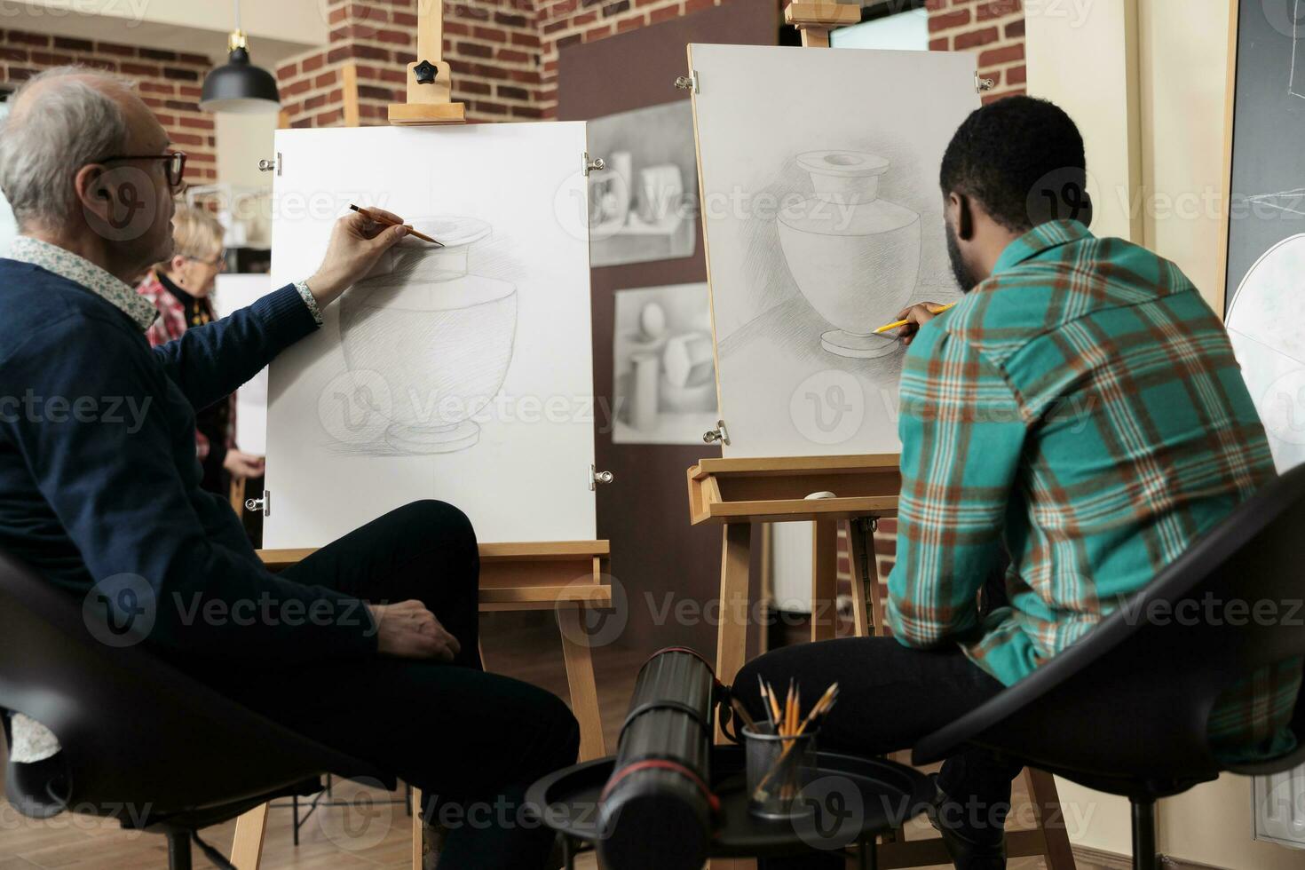 Rear view of two diverse men students sitting at easels practicing still life drawing in art studio. Friends learning new things together, people learn how to draw with pencil during creative workshop photo