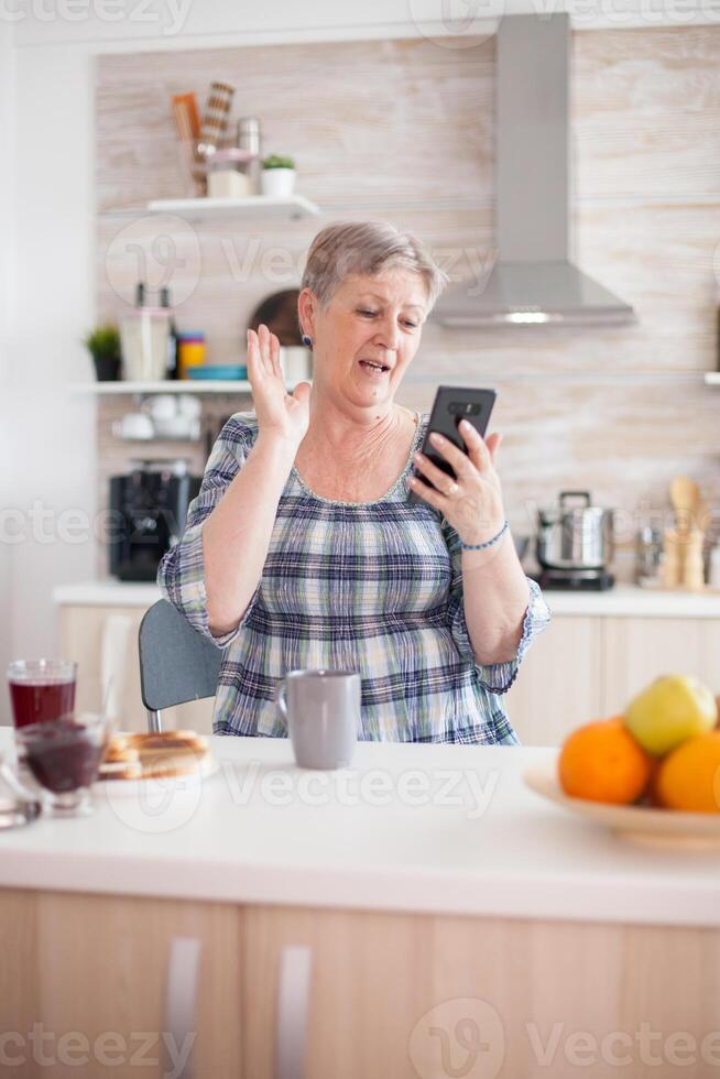 Retired woman saying hello while having a video call with family