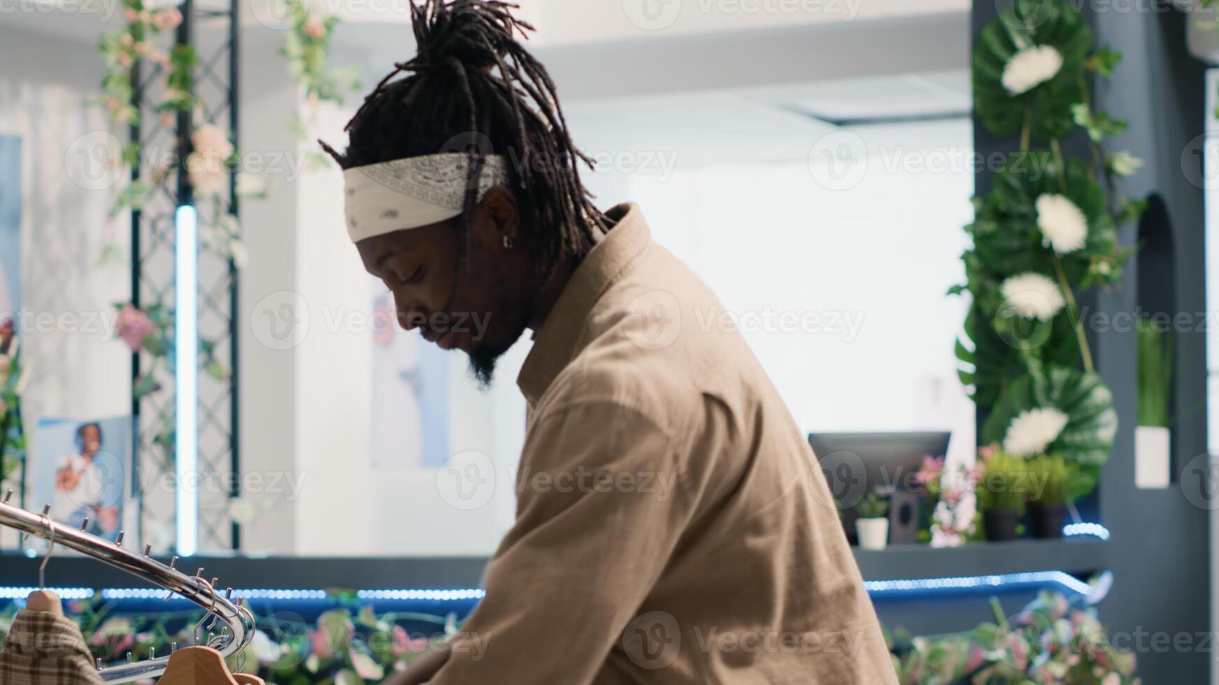 Customer looking at stylish formal clothes on hangers in fancy fashion boutique. Client buying latest exquisite designer clothing men shirts collection in premium showroom photo