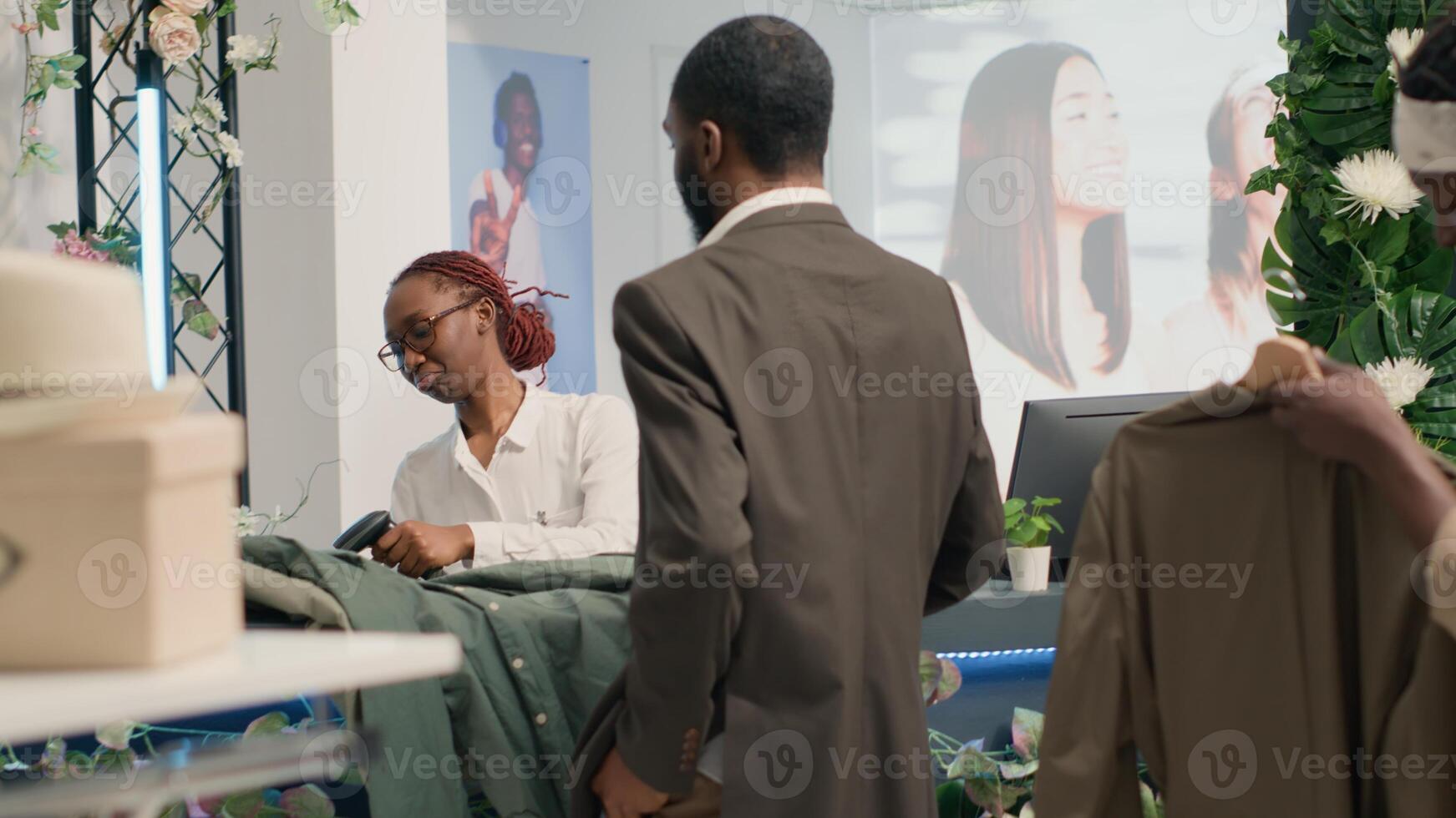 Woman using barcode scanner at clothing store checkout, processing customers bought items while they wait in line. Retail clerk scanning clothes bought by clients in fashion boutique photo