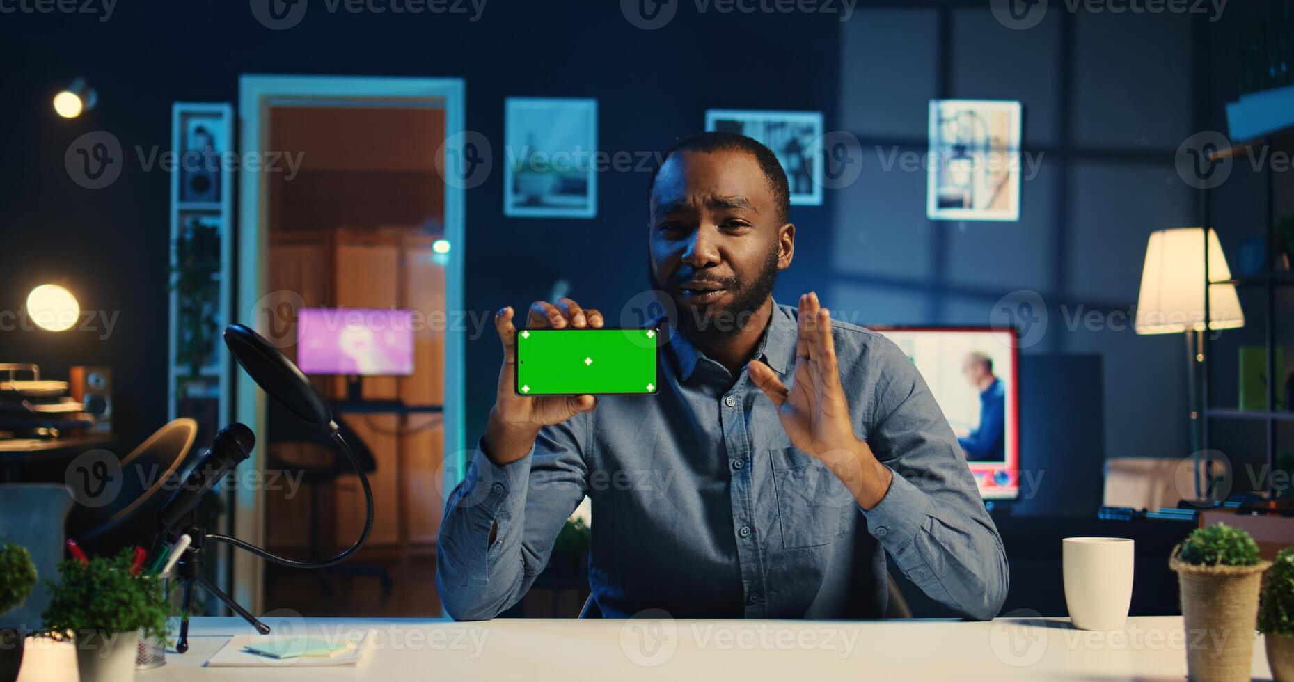 Happy content creator holding chroma key product, being sponsored by tech company to film unboxing review. African american influencer showing mockup screen phone recommendation to viewers photo